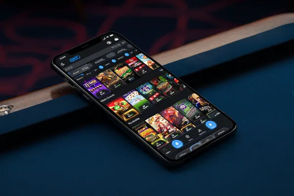 A young woman relaxing with her phone while dynamic casino elements float around her, illustrating the smooth mobile experience offered by the TKPK app.