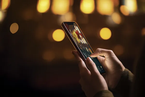 A woman smiling by bright slot machines showing lucky symbols, showcasing the exciting slot offerings at TKPK.